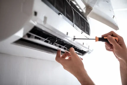 Kombi's technician tightening a screw in an AC unit