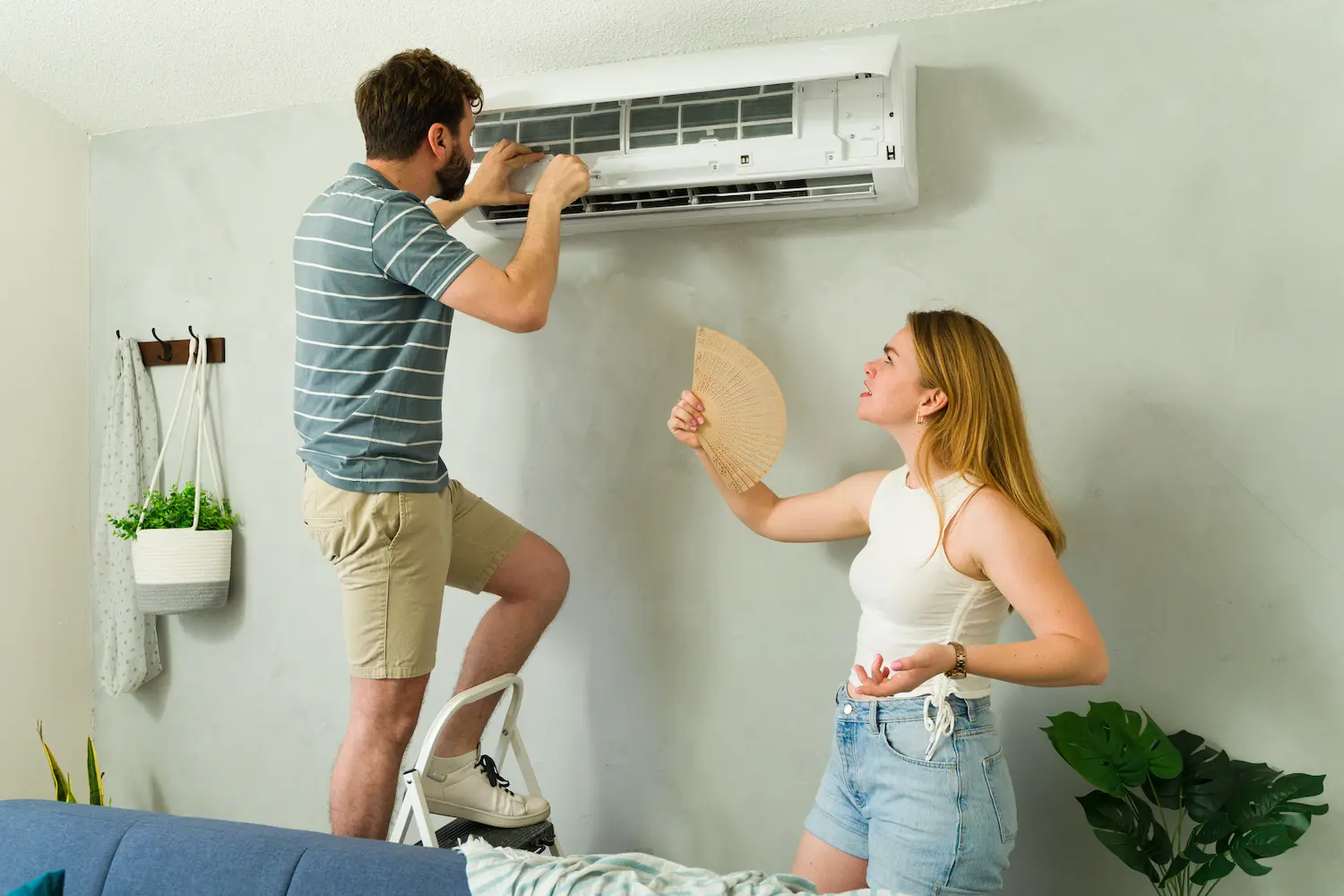 couple trying to fix a broken air conditioner